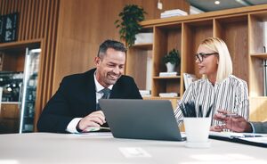 two individuals discussing work on a laptop